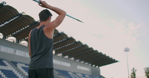 Sportsman doing javelin throw on athletic ground. Male athlete throwing the javelin in the stadium. Athlete in sport clothes at athletic sport track in professional stadium