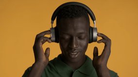 Attractive smiling African American man in headphones moving on music over colorful background
