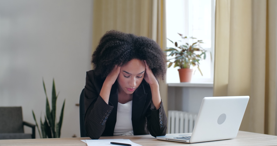 Tired exhausted Afro woman bored of routine work study in office at home with laptop, loses energy, lays head on hands on table, falls asleep long day at workplace, girl feeling sluggish unhealthy Royalty-Free Stock Footage #1057292419