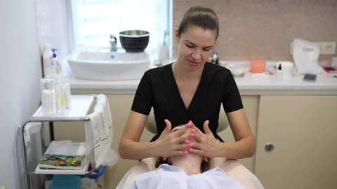 Cosmetologist make face massage for her client in a beauty salon