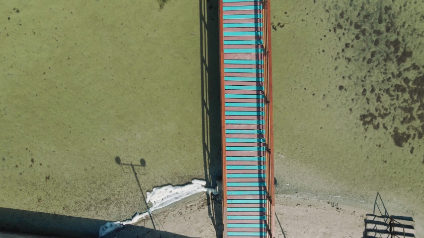 aerial view drone shot long wooden bridge or pier in clear transparent sea water.