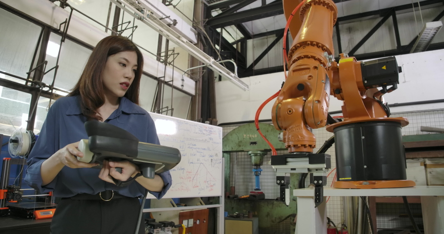 Young Asian Female Industrial Robotics Engineer is Testing and Program Robot Arm in a Research Laboratory with Modern Equipment. People with technology or innovation concept. Royalty-Free Stock Footage #1057299649