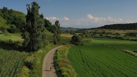 Drone 4k clip with cyclist riding on a beautiful winding road in Transylvania, Romania, in summer season