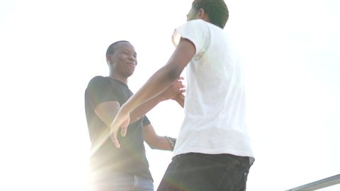 Meeting of two African American men friends. Greeting handshake and hug. Outdoor portret of two black students. Equality and brotherhood concept