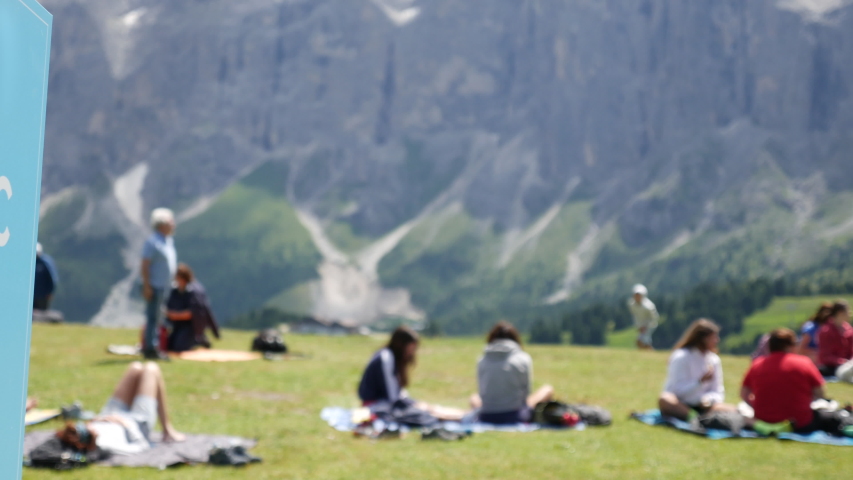 Sign indicating the picnic area. A green alpine meadow with people. Closeup of the sign.