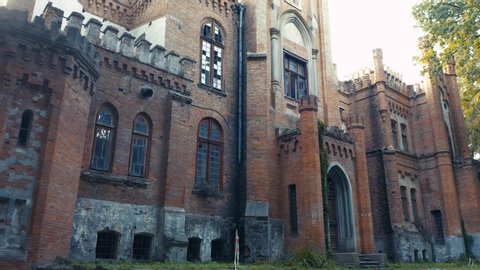 Abandoned 19th century palace (manor or mansion house) with broken windows in Neo-Gothic (Gothic Revival) style. Old deserted castle. Extreme low angle view