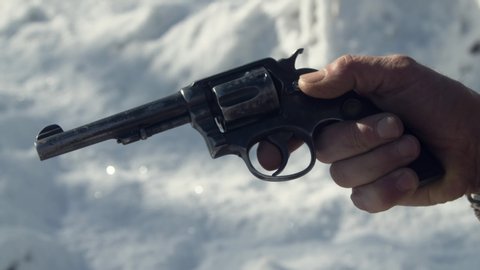 Man checking old western revolver gun, loading gun, snow in the background 