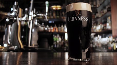 N.NOVGOROOD RUSSIA June 21, 2016 - Zoom in on a glass with cold dark Guinness beer with a thin strip of completely settled foam.Bar background. High quality 4k footage