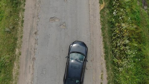Aerial View of Car Avoiding Potholes On An Old Road