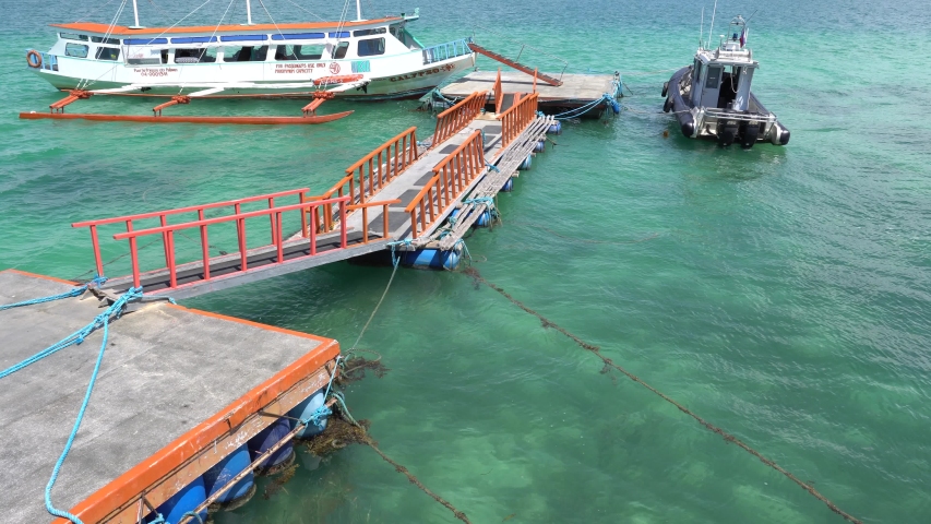 Tourist Boat Anchored On The Blue Ocean Near The Floating Dock In Puerto Princesa, Palawan, Philippines. - wide shot
