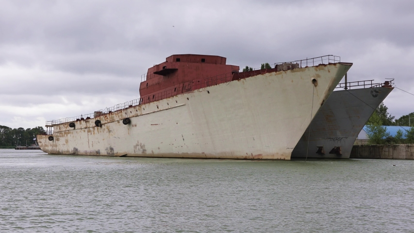 Two old warships are moored on the riverbed against a dramatic sky. Waiting to be sawed and disposed of 
