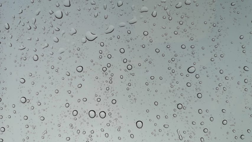 Rainwater drops Falling Down On the Window Glass, Rain Drops On The Windows Glass, Macro shot of water droplets falling.
