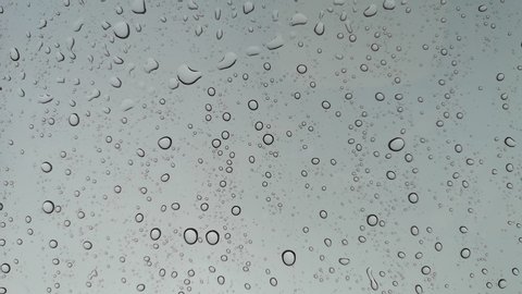 Rainwater drops Falling Down On the Window Glass, Rain Drops On The Windows Glass, Macro shot of water droplets falling.

