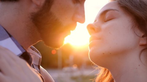 close up on young couple kissing in the reflected light of the sunset