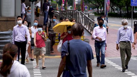 Singapore / August 12, 2020 : Group of people wearing mask  crossing a road in Chinatown. Crowded intersection.