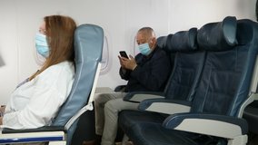 4K: Male Asian Airplane Passenger using a Phone and wearing Face mask on plane journey. Air Travel. Tracking Shot. Stock Video Clip Footage