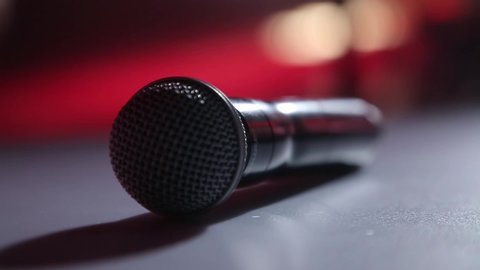 The microphone lies on the stage against the background of a concert show, performance or karaoke. Dynamic background color bokeh. The concept of a musical instrument.	