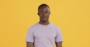 Flirt concept. Playful african american guy pointing to camera, choosing you, yellow studio background