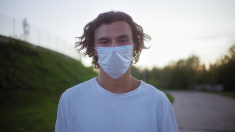 Punk man portrait wearing a protective medical mask, covid safety, coronavirus pandemic, millennial boy on street, generation z students university life