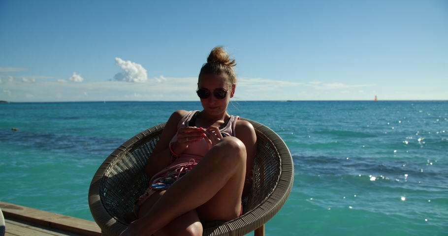 Young woman during vacation at the Caribbean Sea is enjoying the sun, chilling and sunbathing on the wicker basket.