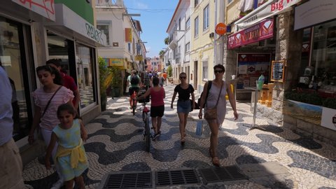 CASCAIS, PORTUGAL - JULY 16, 2019: Unidentified people walk at summer day along pedestrian shopping street at Cascais, famous seaside town near Lisbon. Many stores and restaurants around