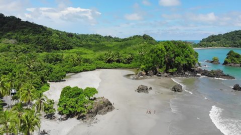 Aerial shot of Espadilla beach and tropical forest of National Park, Manuel Antonio, Costa Rica. Sunny weather, clear blue green water.
