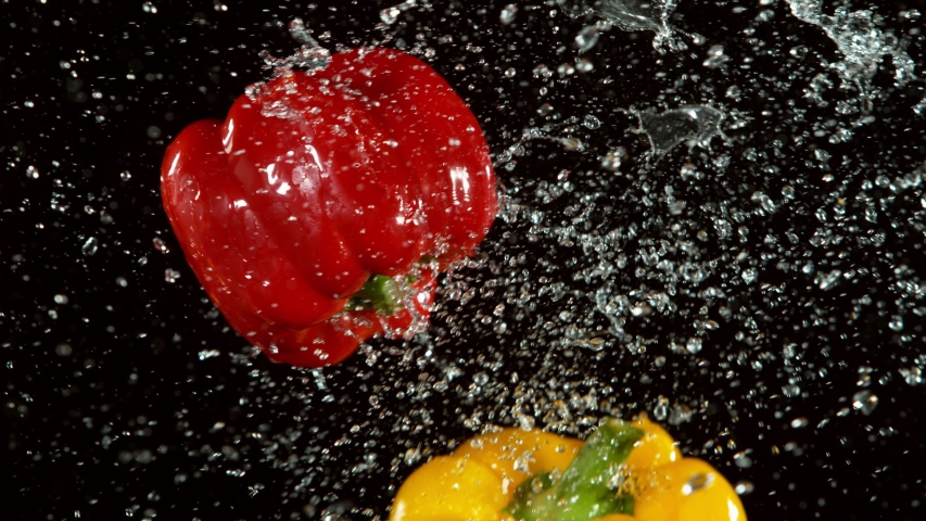 Super slow motion of coloured peppers flying up in the air with water splashes. Filmed on high speed cinema camera, 1000 fps.