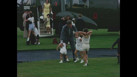 1960s: John F Kennedy and Robert Kennedy exit helicopter, children run toward helicopter, Kennedys hug children.