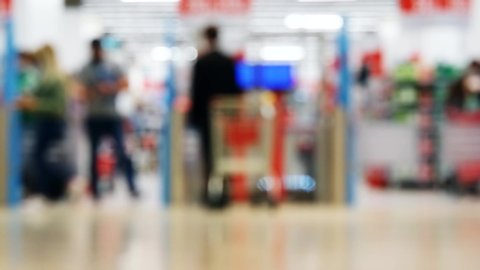 Defocused shopping mall interior background. Silhouettes of shoppers with bags and purchases.