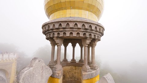 SINTRA, PORTUGAL - JULY 16, 2019: Move forward and look down to access road and gates. Watch through small columns of decorative turret at corner of wall. Famous landmark of Sintra, Palacio da Pena