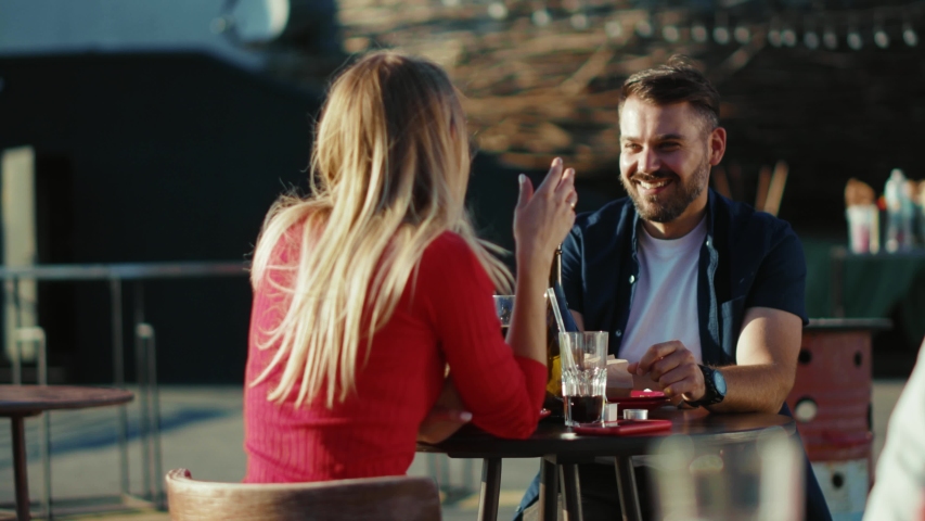 Happy young relaxing man and woman drinking cocktail smiling in street cafe time together date food girlfriend meal cheerful portrait slow motion Royalty-Free Stock Footage #1057358881