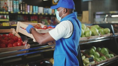 Shot of african american sales wear gloves and mask consultant working in supermarket market store black food seller shop grocery holding job organic market staff slow motion