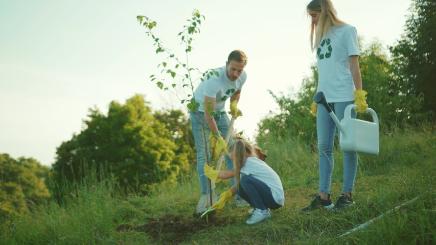 Close up cute family with dog plant tree stand add water to the tree care green garden man environment agriculture planet ecology teamwork gardening slow motion