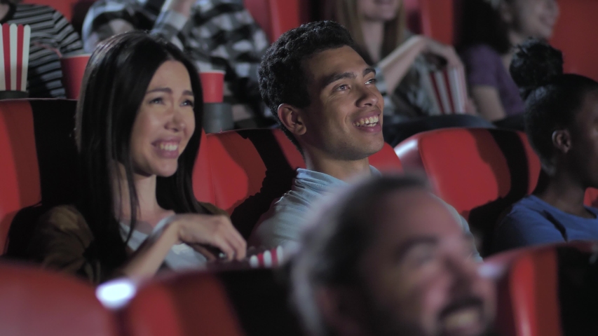 Closeup of nice asian couple enjoying comedy in movie theater, cute brunette female eating popcorn and bursting from laughter together with boyfriend. Laughing diverse viewers watching movie in cinema | Shutterstock HD Video #1057360654
