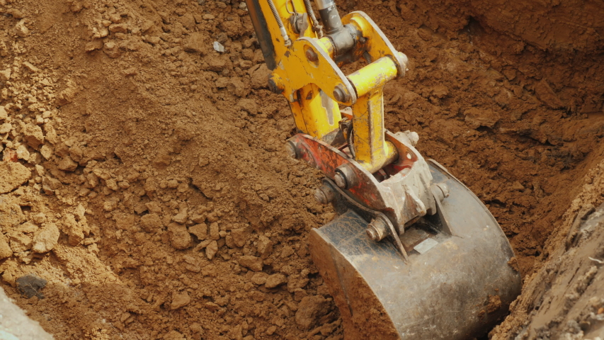 Large digger bucket extracts soil from trench Royalty-Free Stock Footage #1057361008