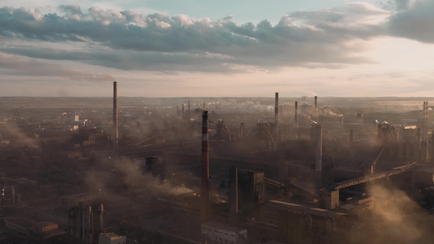 Drone shot of industrial zone with thick smog and burning fossil fuels. Zoom in aerial shot of factory zone shot from top, air pollution and soot in many factory chimneys in city area | Shutterstock HD Video #1057361683