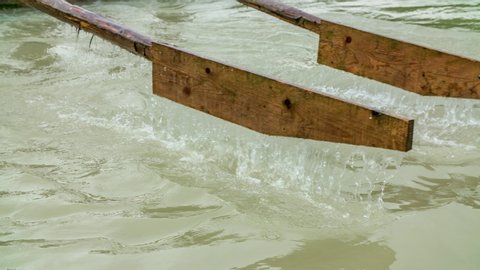Rowers work oars. Handmade wooden oars row cloudy green water. Large ferry steering oars. Closeup