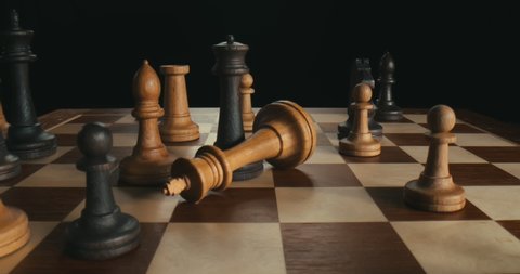 Close up of businessmen playing chess. Black figures win checkmate. Side view of black queen defeating white king during chess game isolated on black background