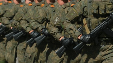 Parade military army soldiers with assault rifle ak-47 in hands march even formation closeup. Officers walk street hold in arm kalashnikov firearm 4K. Soldier marching show kalashnikov ak 47 close up.