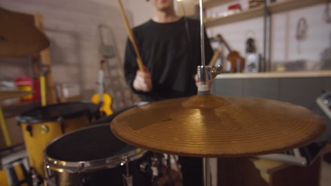 Close-up drum plate focused shot of modern musician playing drums in recording studio at home