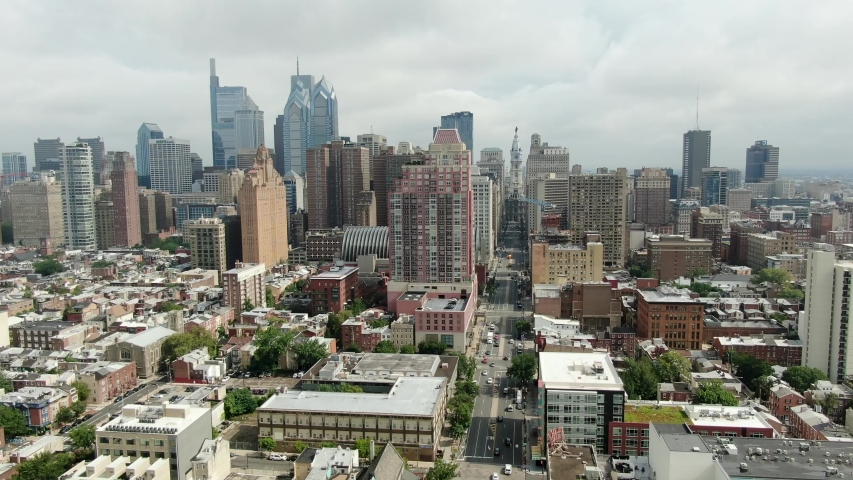 Aerial pullback shot reveals Philadelphia skyline, looking north on Broad Street toward City Hall on cloudy summer day