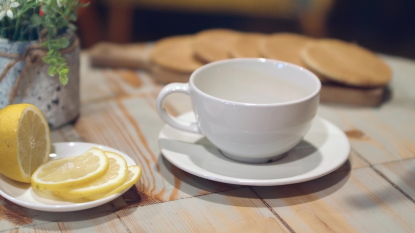 Tea being poured into white tea cup. Dessert and hot drink. Lemon slices. Tea time. Slow motion.  Breakfast concept. Royalty-Free Stock Footage #1057374241