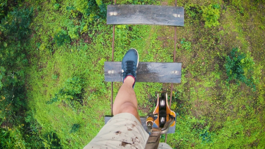 POV Shot Of A Man Walking On The High Rope Obstacle With Small Wooden Planks In The Lush Jungle In Chiang Mai, Thailand - high angle