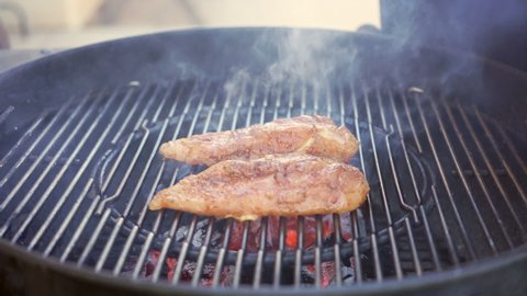 Barbecuing perfectly spice-rubbed or marinated chicken breasts on the grill - slow motion