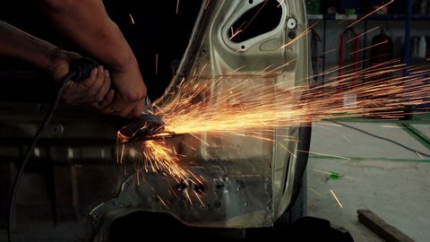 Worker using electric grinder machine cutting steel. Steel cutting machine in auto body repair shop