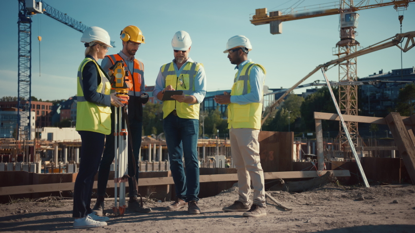 Diverse Team of Specialists Use Tablet Computer on Construction Site. Real Estate Building Project with Civil Engineer, Architect, Business Investor and Surveyor with Theodolite Discussing Plans. Royalty-Free Stock Footage #1057388140