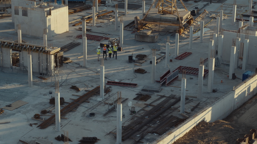 Aerial Flight Over a New Constructions Development Site with Diverse team of Engineers and Architects Discussing Real Estate Projects. Heavy Machinery and Construction Workers are Working in the Area. Royalty-Free Stock Footage #1057388173