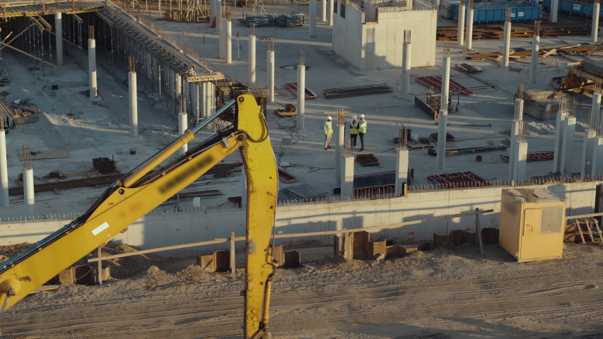 Aerial Flight Over a New Constructions Development Site with Diverse team of Engineers and Architects Discussing Real Estate Projects. Heavy Machinery and Construction Workers are Working in the Area. Royalty-Free Stock Footage #1057388173