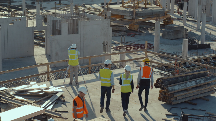 Aerial Flight Over a New Constructions Development Site with Diverse team of Engineers and Architects Discussing Real Estate Projects. Heavy Machinery and Construction Workers are Working in the Area. Royalty-Free Stock Footage #1057388215