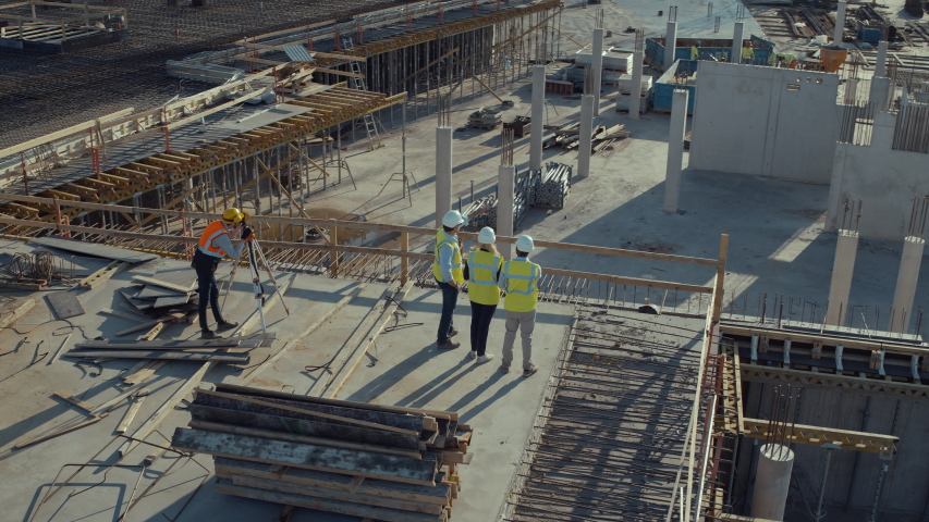 Aerial Flight Over a New Constructions Development Site with Diverse team of Engineers and Architects Discussing Real Estate Projects. Heavy Machinery and Construction Workers are Working in the Area. Royalty-Free Stock Footage #1057388221
